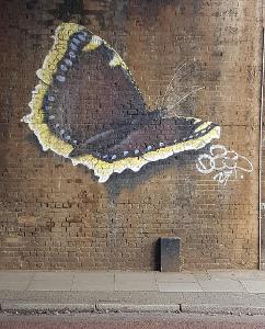 Who is famous for their signature butterfly motif in their street art?