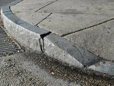 When parallel parking uphill with a curb, which direction should you turn your wheels?