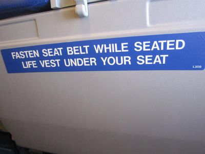 When should you wear your seat belt while seated on the airplane?