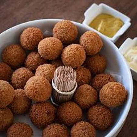 Bitterballen Amsterdam's snack. Bitterballen are a Dutch meat-based snack, typically containing a mixture of beef or veal, butter, flour for thickening, parsley, salt and pepper, resulting in a thick roux. Most recipes include nutmeg and there are also variations using curry powder or that add in finely chopped vegetables such as carrot. The ingredients are combined and cooked, then refrigerated for the mixture to firm up. Once firm, the filling is rolled into balls roughly 3 to 4 cm in diameter, then battered in a breadcrumb and egg mixture and deep-fried. Wiki
