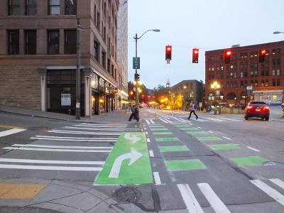 How should you signal a left turn when riding a bike?