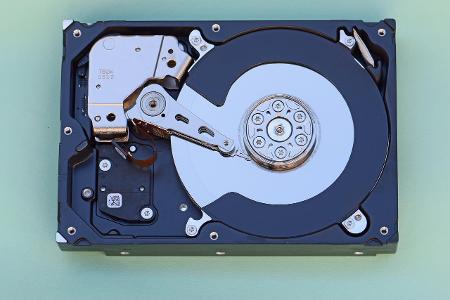 What is the purpose of the actuator arm in a hard disk drive?