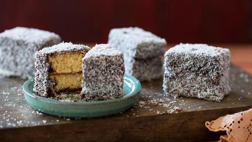 Lamington A lamington is a small square of sponge cake, filled with jam, dipped in chocolate and rolled in shredded coconut.
