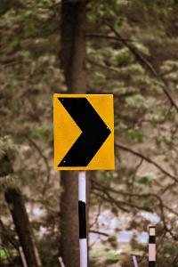What does a round yellow traffic sign with black arrows indicate?