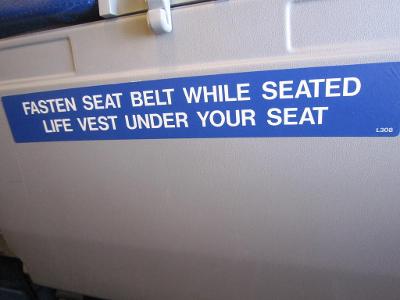 When should you wear your seat belt while seated on the airplane?
