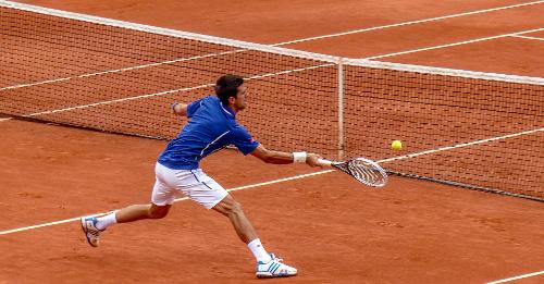 In doubles tennis, what is a beneficial strategy for the serving team?