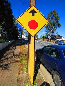 What does a yellow diamond road sign with two opposite arrows indicate?
